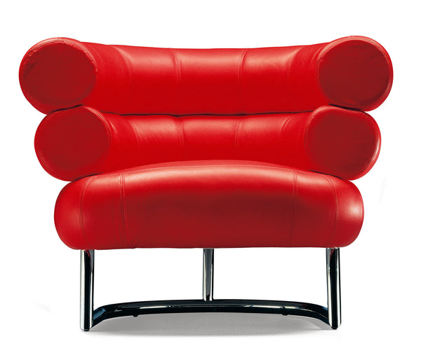 A red upholstered curved armchair with a unique design, featuring a bold, streamlined shape and supported by a metallic frame.